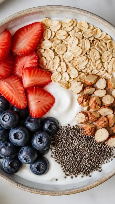 Greek yogurt bowl topped with blueberries, strawberries, oats, chia seeds, and chopped almonds.